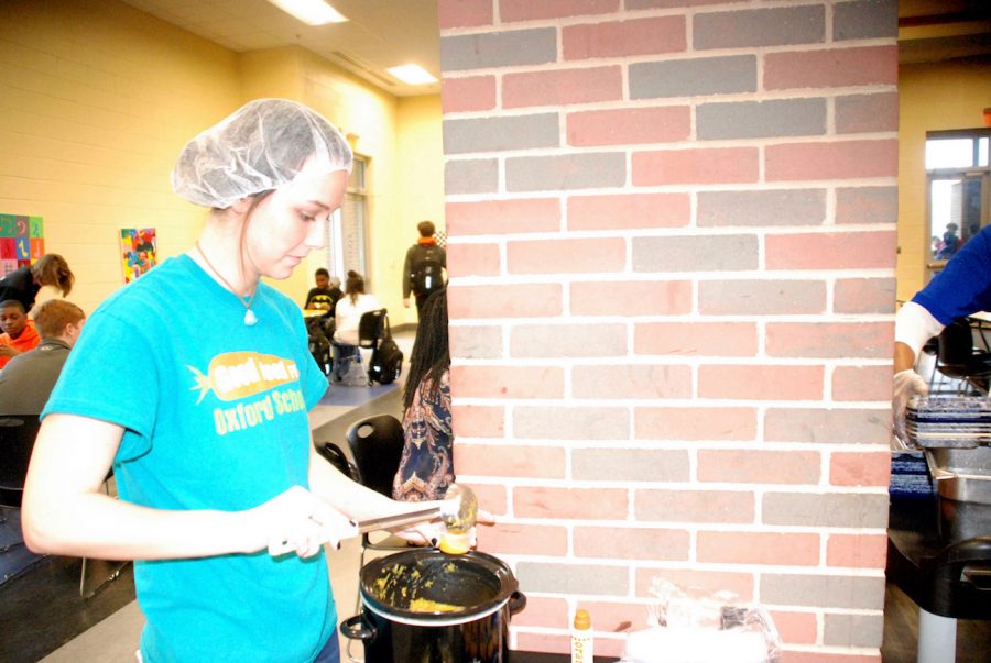 A member of Good Food for Oxford Schools fills a cup with a sample of butternut squash soup to serve to students during lunch.