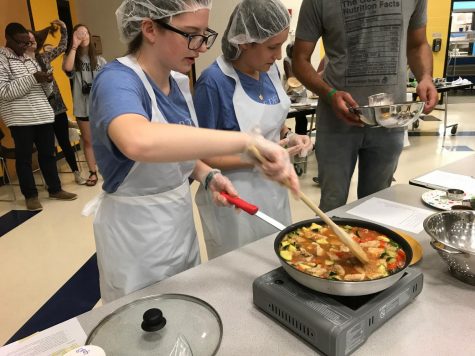 Junior Emily Hollowell (left) and sophomore Justine Perrier (right) of the Delicious Duo team cook their meal of choice for the Iron Chef competition on April 30.