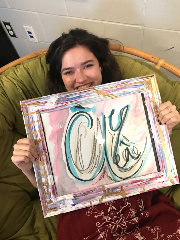 Senior Neely Mullen holds up a painting that represents the name of the club, À Crea, and logo of the new art club. 