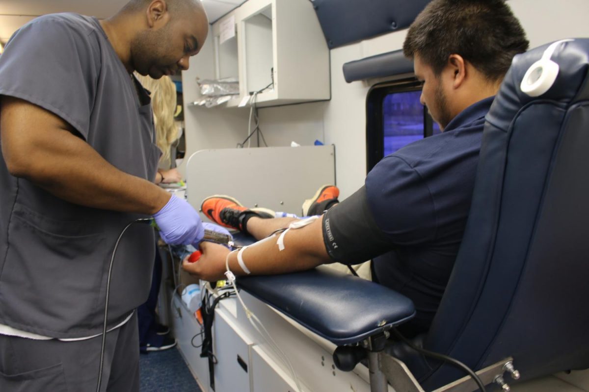 Nurse Gregory Sam draws blood from junior Carlos Moreno’s arm. United Blood Services comes to Oxford High School twice a year for the blood drive.