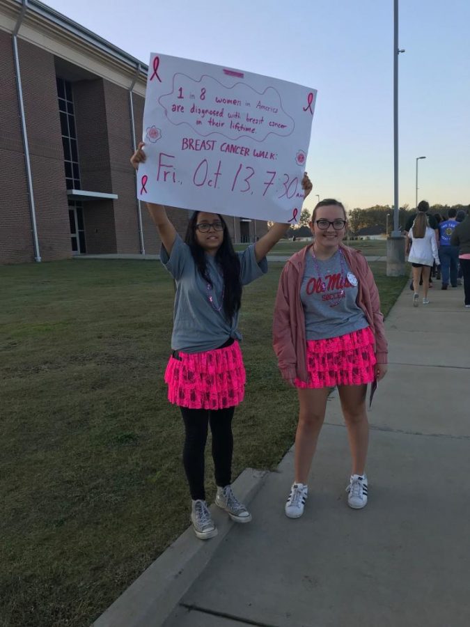 Freshmen Freida Lopez and Alex Johnson hold a sign during the Breast Cancer Awareness walk on Oct. 13.