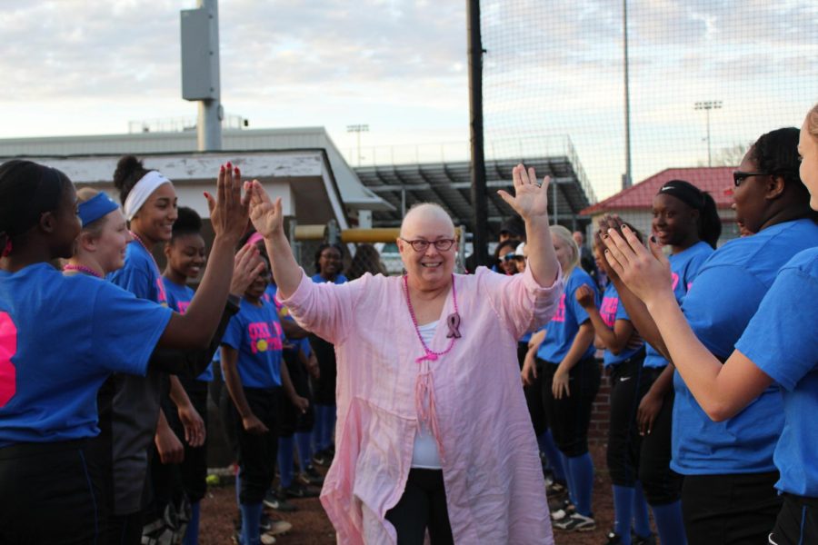 Dr. Barbara Lowe walks through the team huddle giving the players high fives. This is the team's first year helping with the event. 