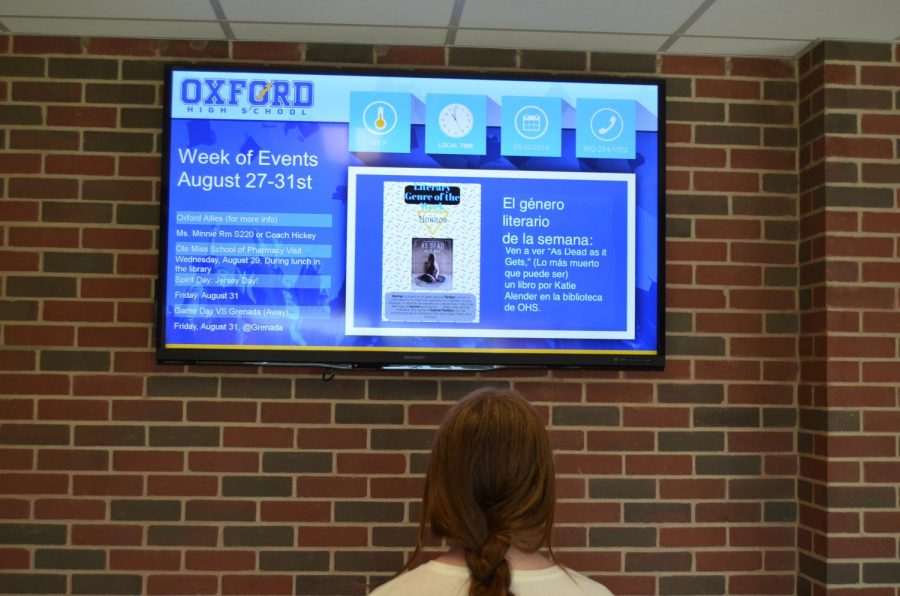 A student looks at the translated version of the school announcements on the televisions in the hallway. Spanish teacher Emily Maples has been working to implement more Spanish translations throughout the school.
