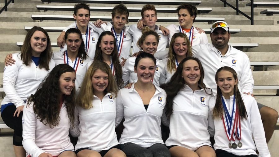 Members of the swim team smile with their head coach Robert Gonzales after their state meet. Overall, the team placed third at the meet on Oct. 27. 