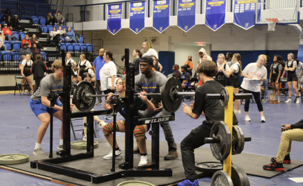 Greyce Brown, sophomore, competes at a powerlifting meet. Her spotters include Jackson Doss, senior, and Bryce Wicker, senior.