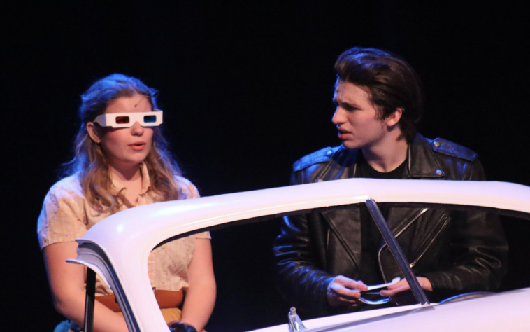 Seniors Ann Luckett Montgomery and Bradley Ramsey sit in car while performing the drive in movie scene. They played the leads, Sandy and Danny, in “Grease.”